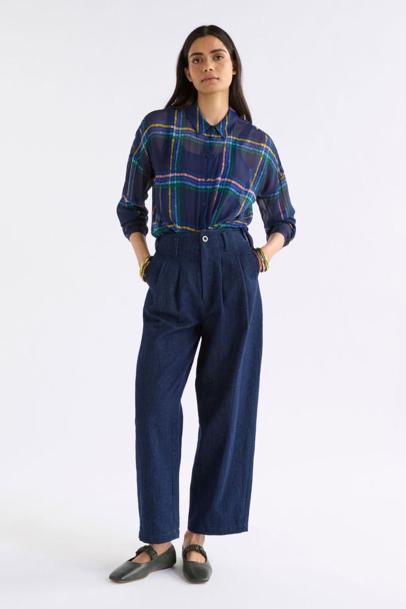 Woman wearing a plaid shirt and blue pants on a white background