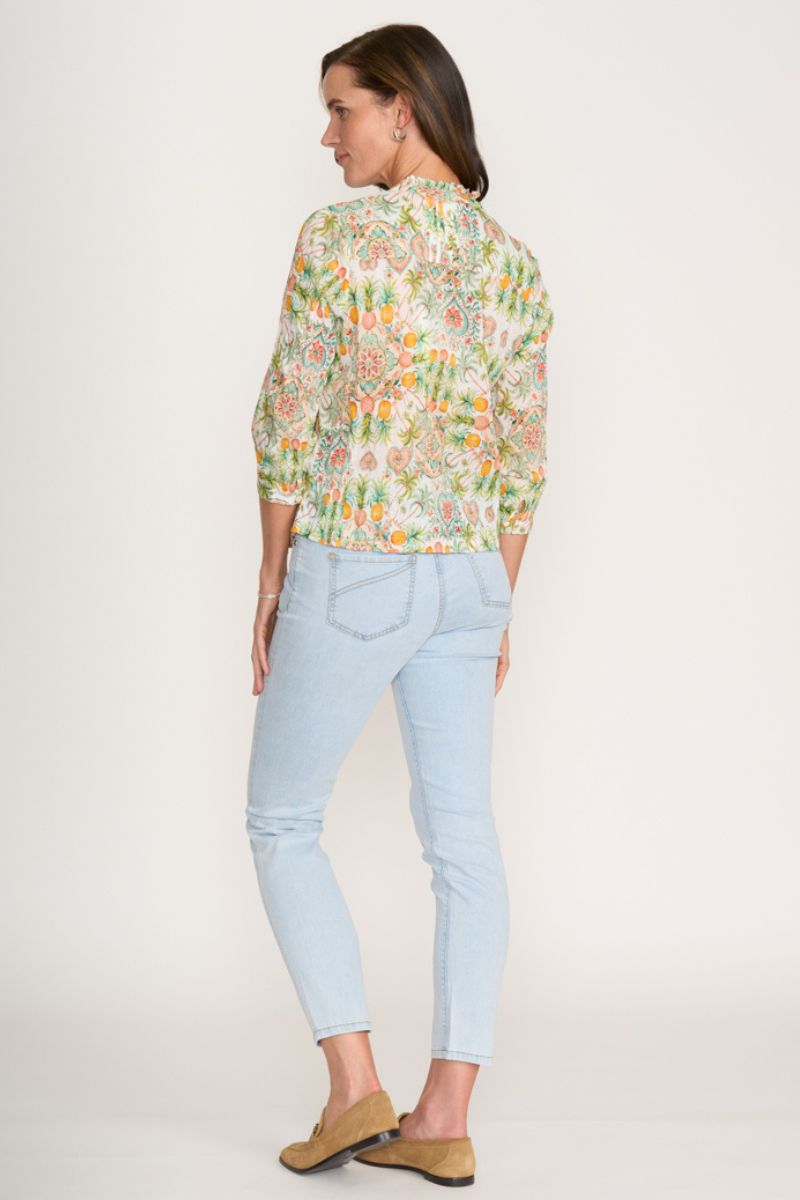 Woman wearing a floral blouse and light blue jeans on a white background