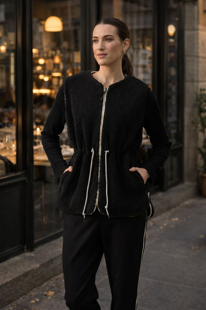 Woman Wearing foil clothing top kat reversible gilet in black with cream piping in a melbourne street 