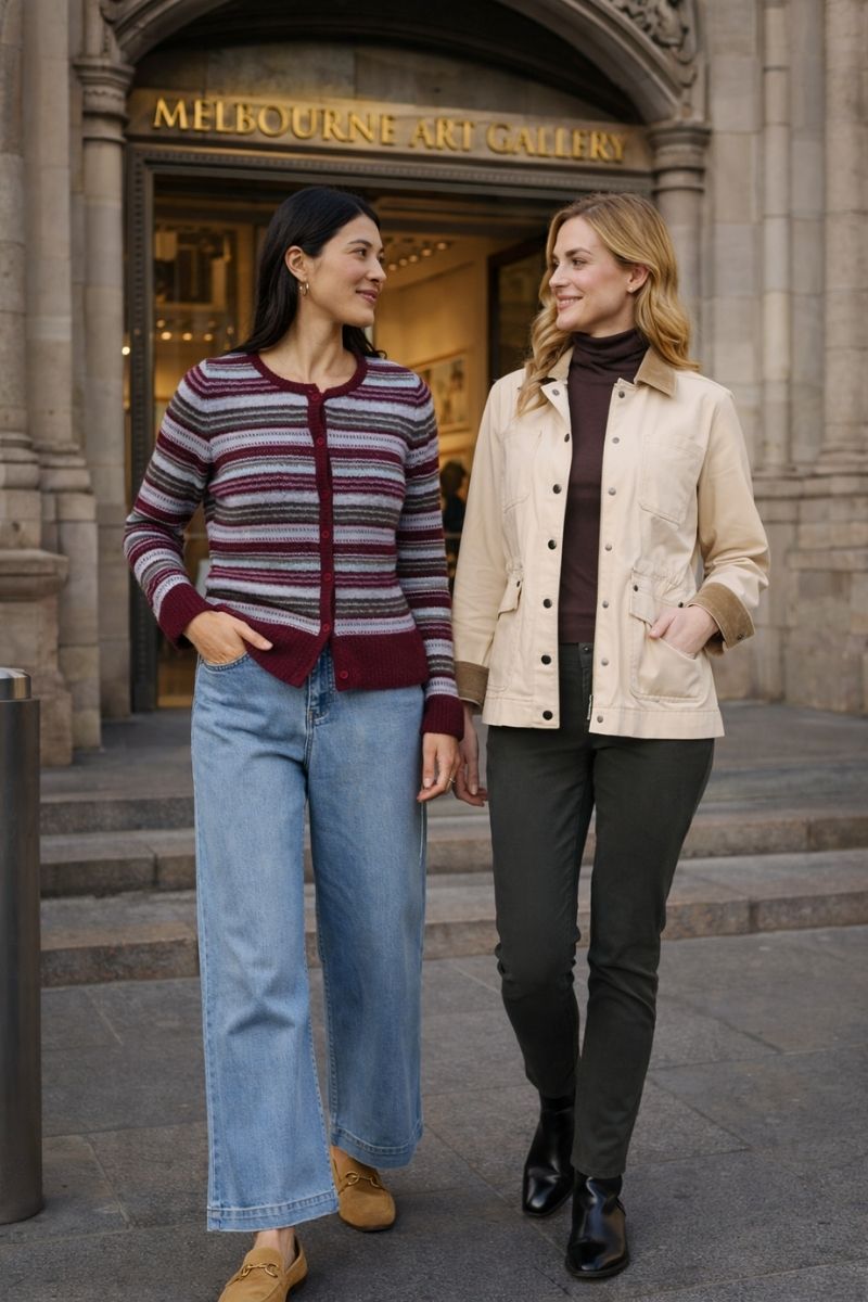 Two women walking outside the melbourne art gallery wearing hidden treasures jacket in cream cashmere colour and the Isle be mine striped cardigan in Cherry grey marle and light blue