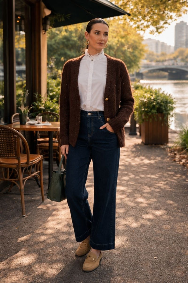 Woman wearing the glow getter cardi in coffee colour with gold buttons standing on the side of the yarra