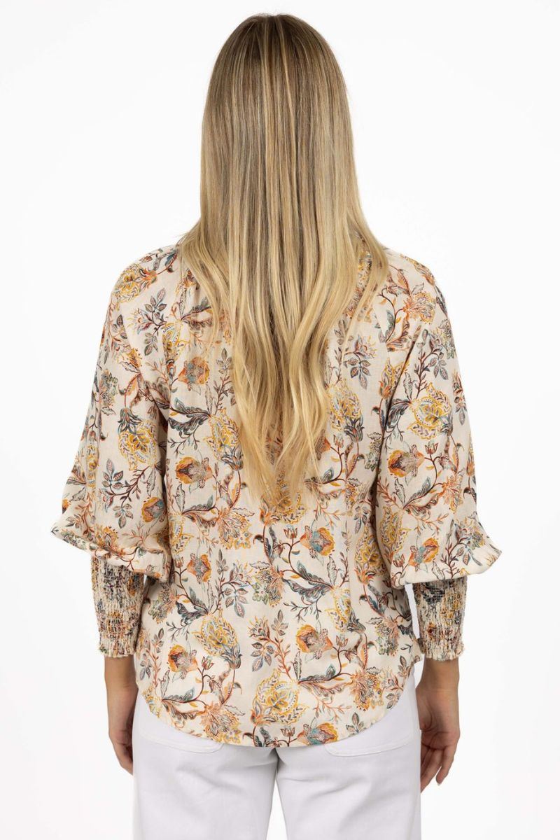 Back view of woman wearing a floral blouse with long blonde hair on a white background