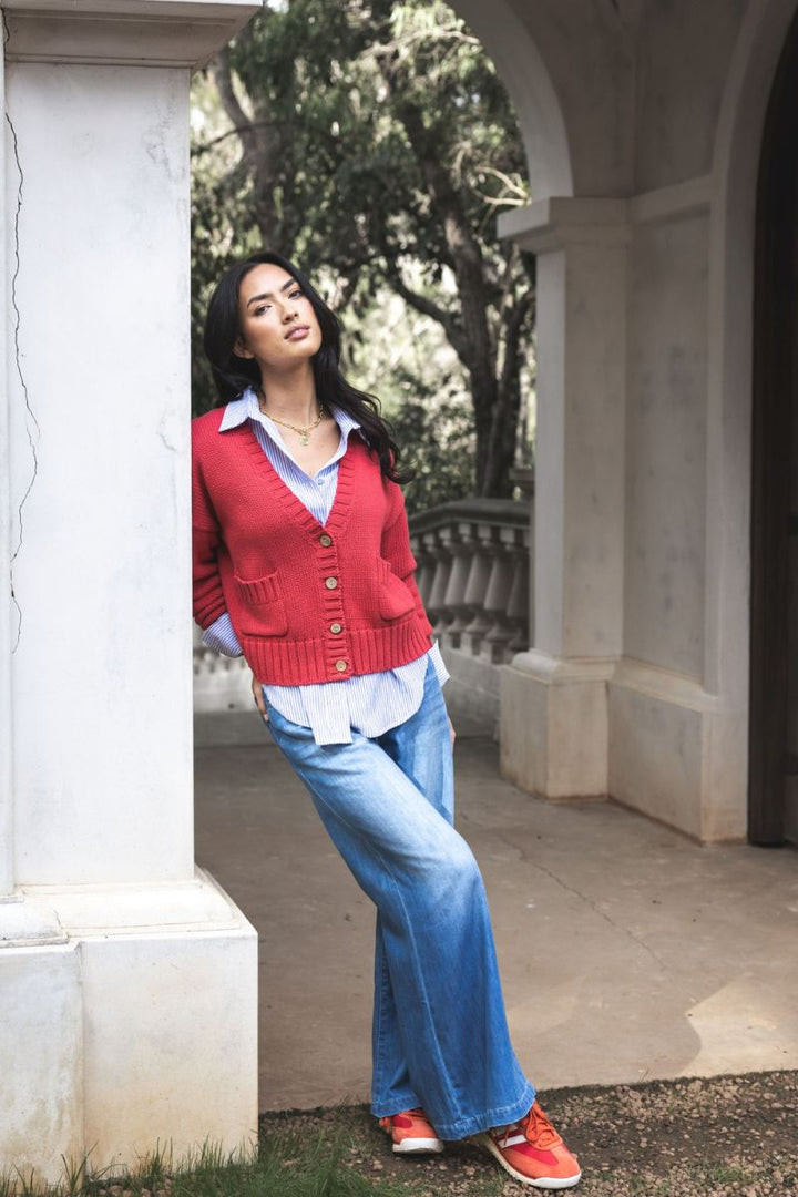 Woman wearing Ryder Jean in Blue Wash by Humidity Lifestyle HW26400 front view in outdoor setting with the nala stripe shirt under a red cardigan