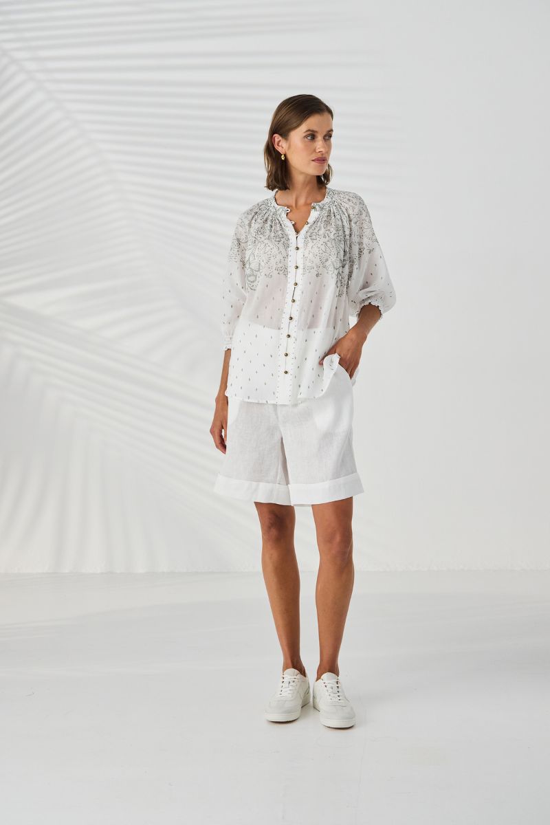 Woman wearing Lania Novo Shirt in white with white shorts against a white background