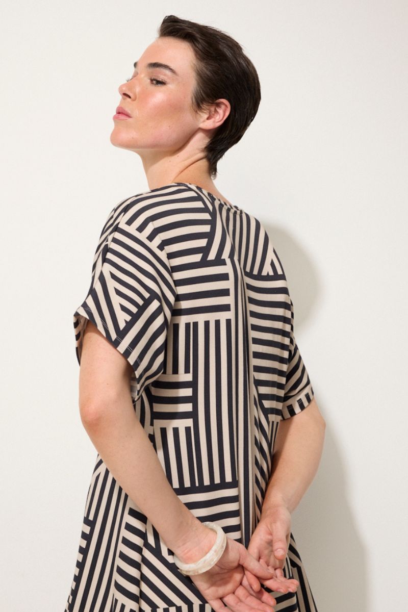 Woman wearing a black and white striped dress against a plain background