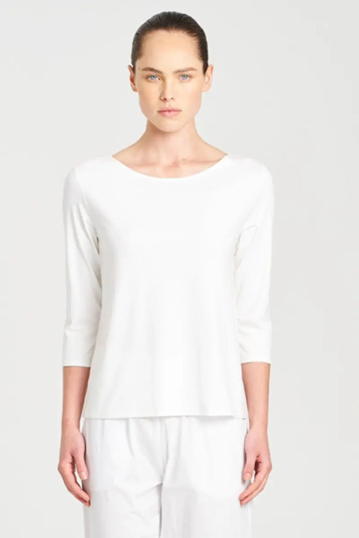Person wearing a white long-sleeve top and pants on a light gray background