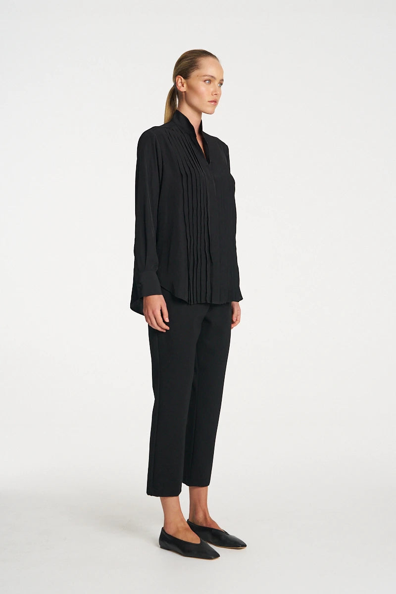 Woman wearing Mela Purdie Balcony Blouse F67 8970 in Black, side view showing the curved hem