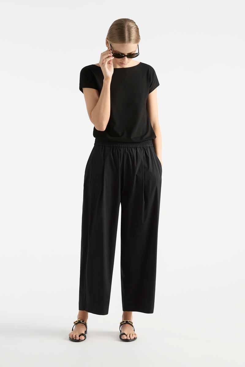 Woman wearing Raglan Shell in Black by Mela Purdie F01 212, front view styled with sunglasses.