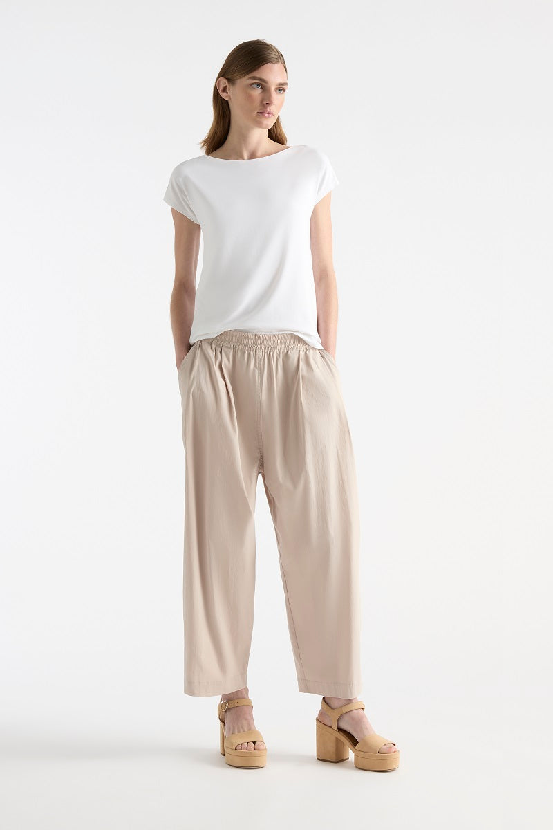 Woman wearing Raglan Shell in White by Mela Purdie F01 212, front view with one hand at the hip.