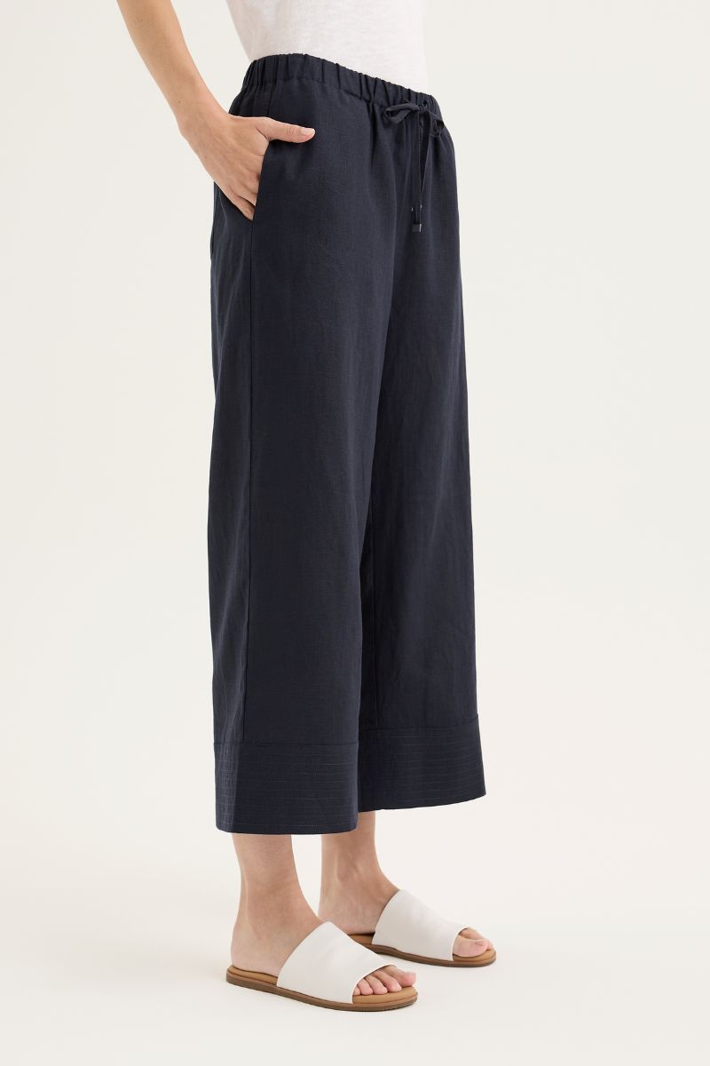 Person wearing navy wide-leg pants with a white background
