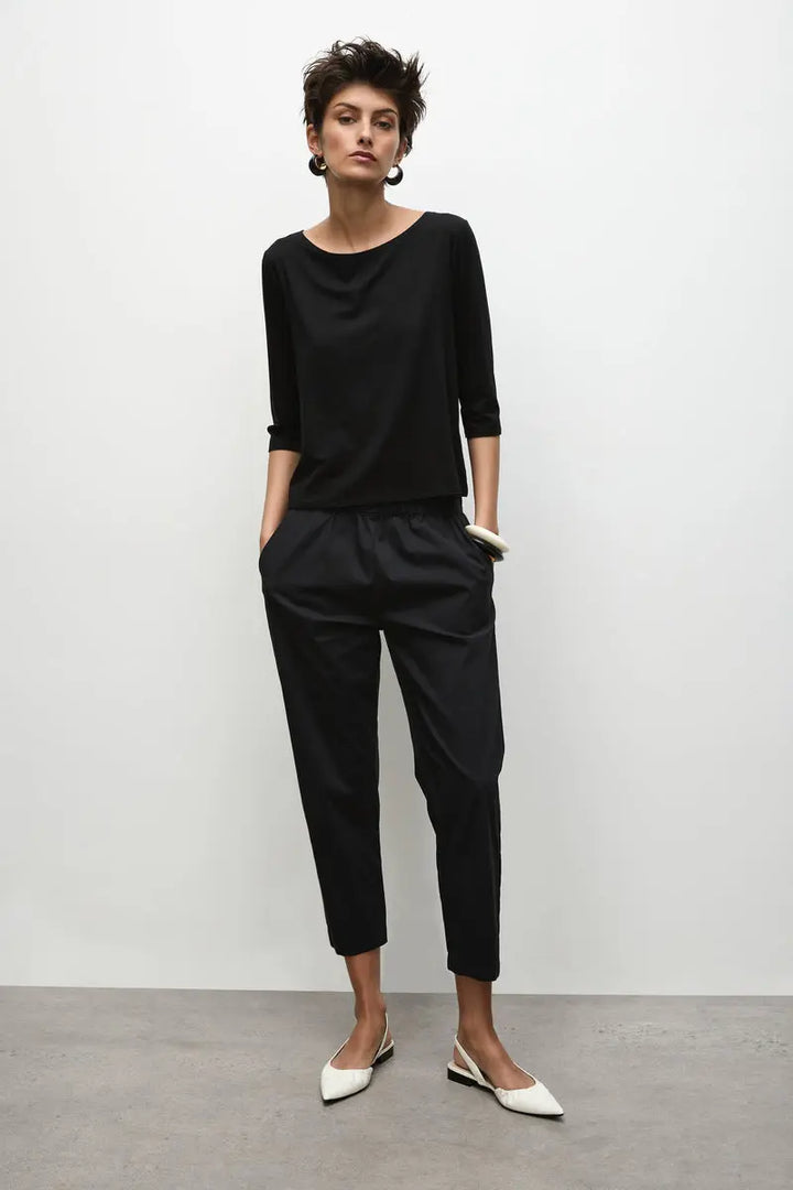 Woman wearing Nomad Pant in Microprene F65 1478 by Mela Purdie in Black, front view with hands in the pockets.