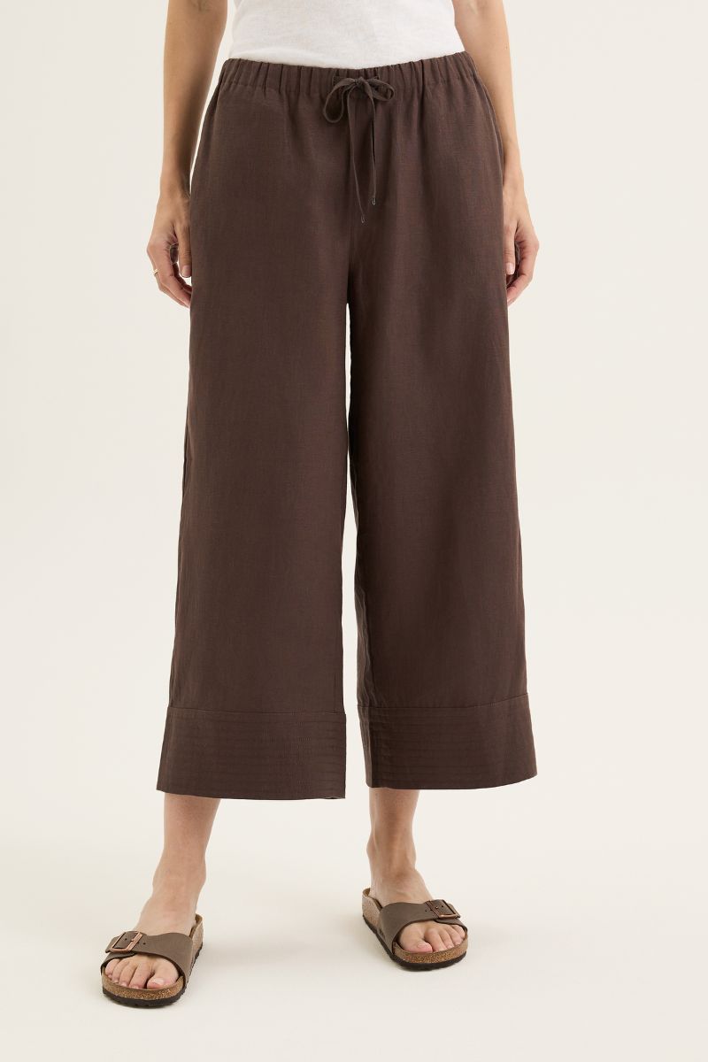 Person wearing brown wide-leg pants on a white background