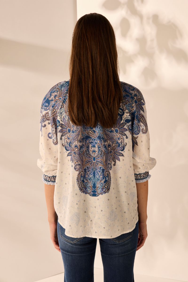Back view of Woman wearing a patterned blouse with a neutral background