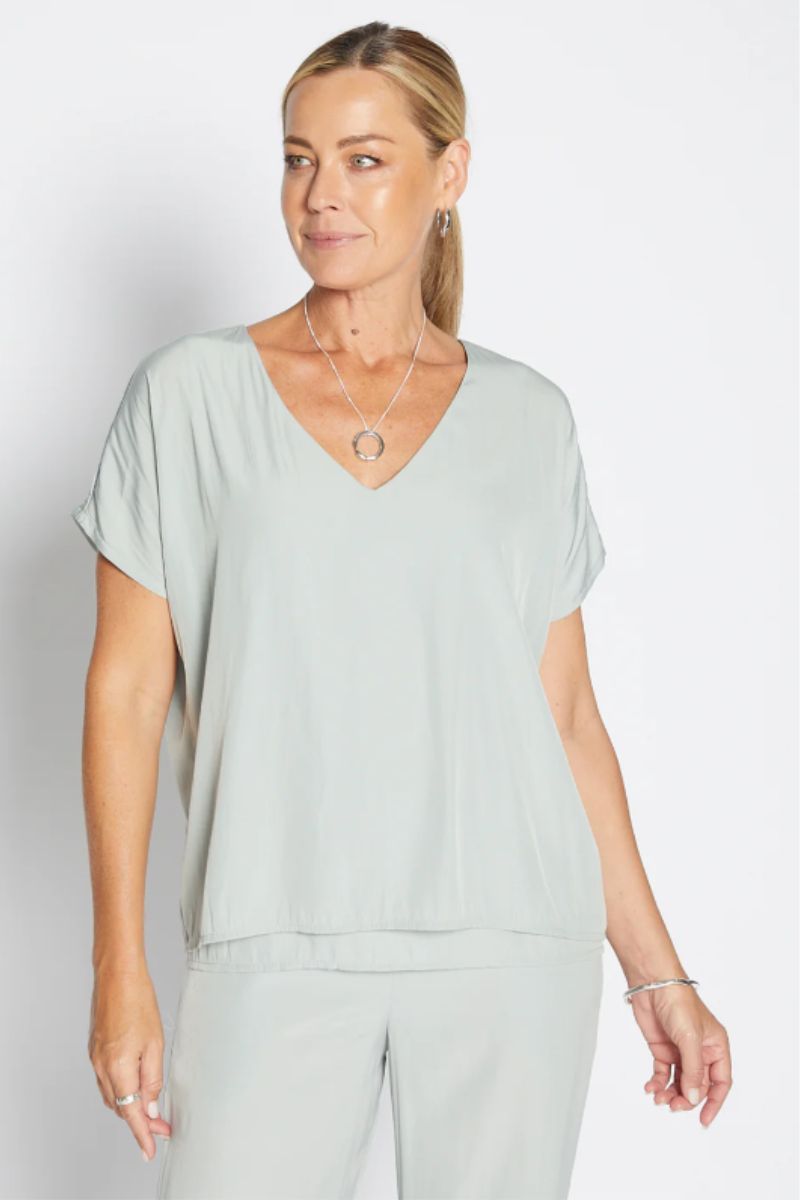 Woman wearing a light green top and pants on a white background