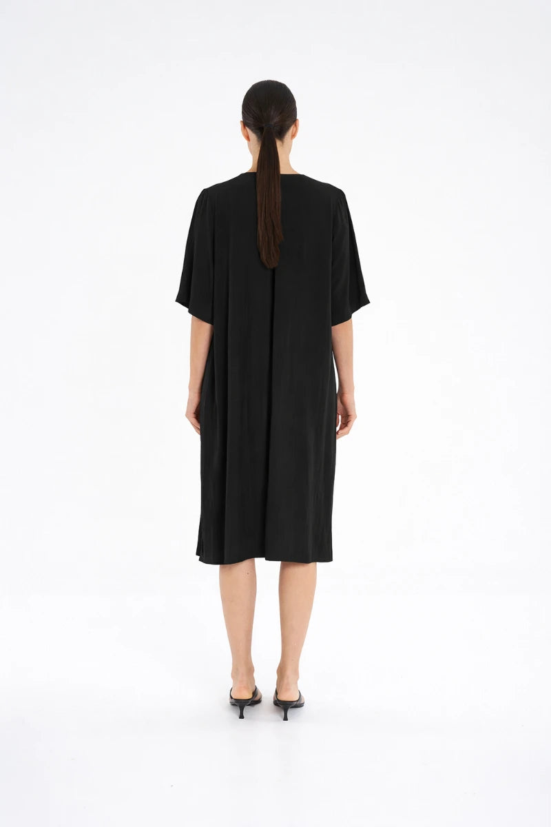 Woman wearing Plaza Dress in Black by Mela Purdie F67 3004, back view showing the centre-back pleat.