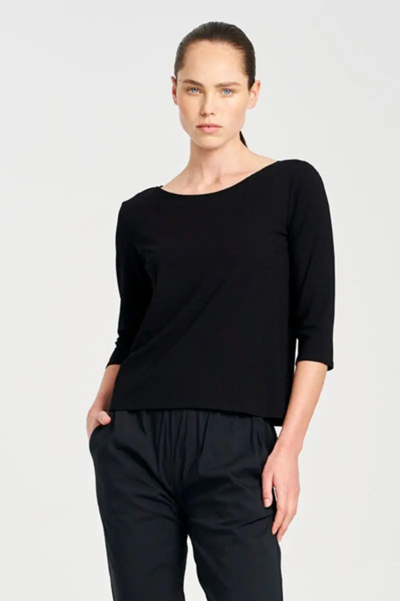Woman wearing a black top and black pants on a light gray background