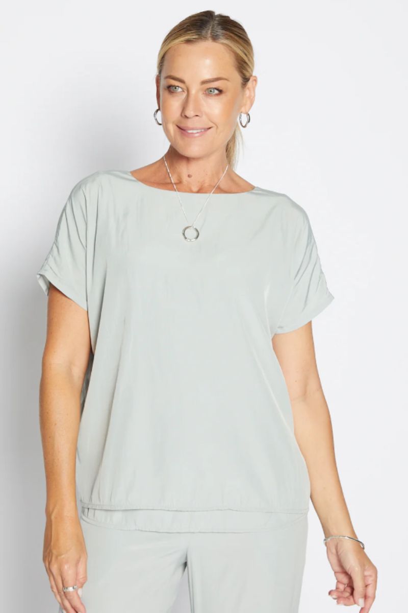 Woman wearing a light green top and pants on a white background
