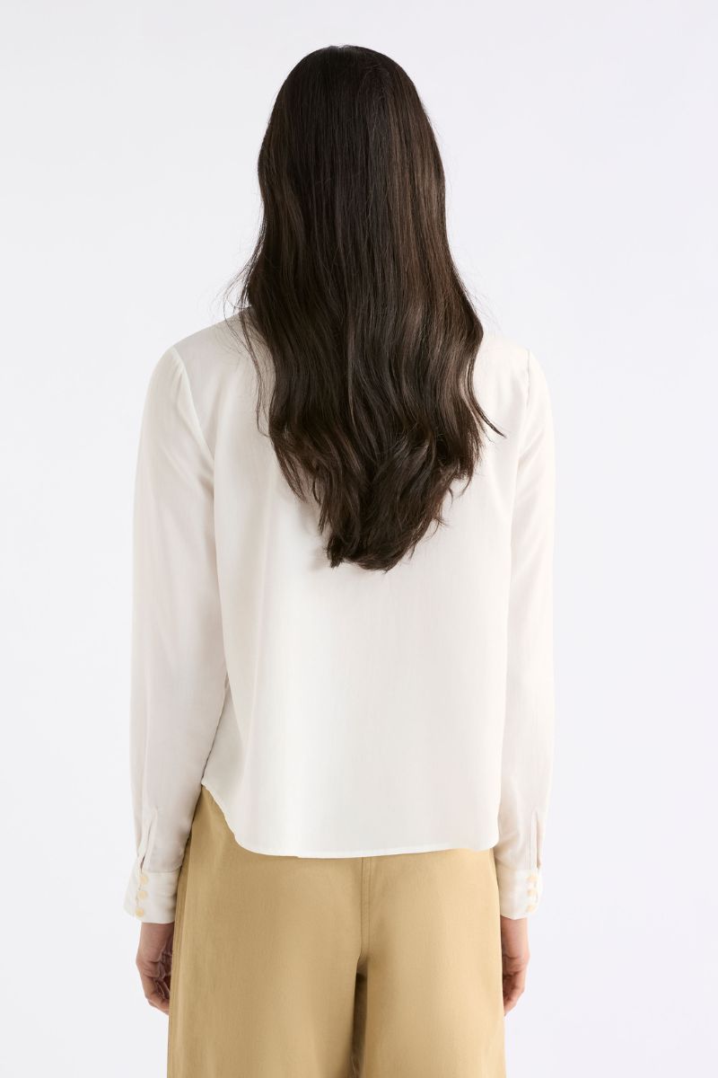 Woman wearing a white blouse and beige pants on a white background