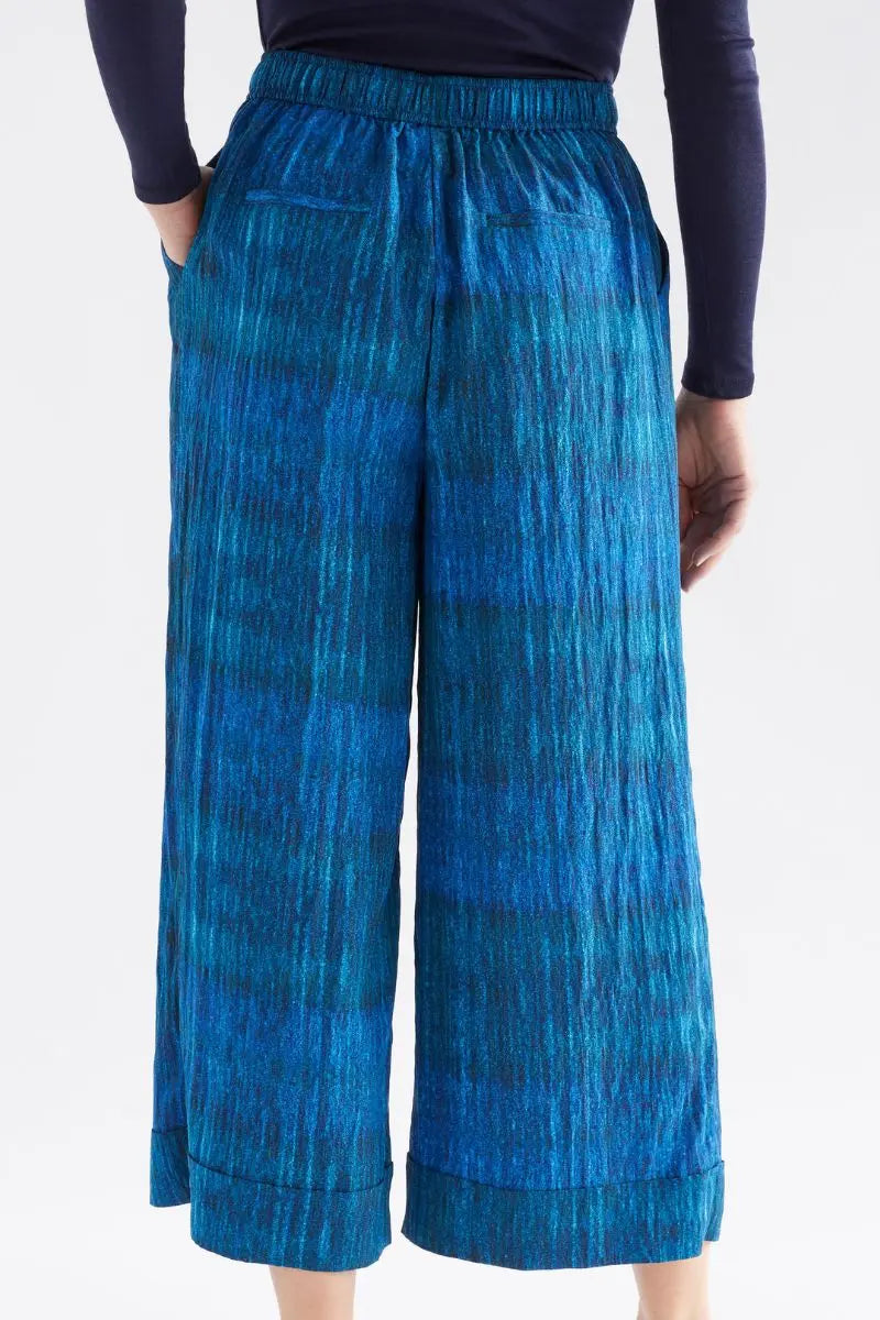 Blue patterned pants worn by a person on a white background