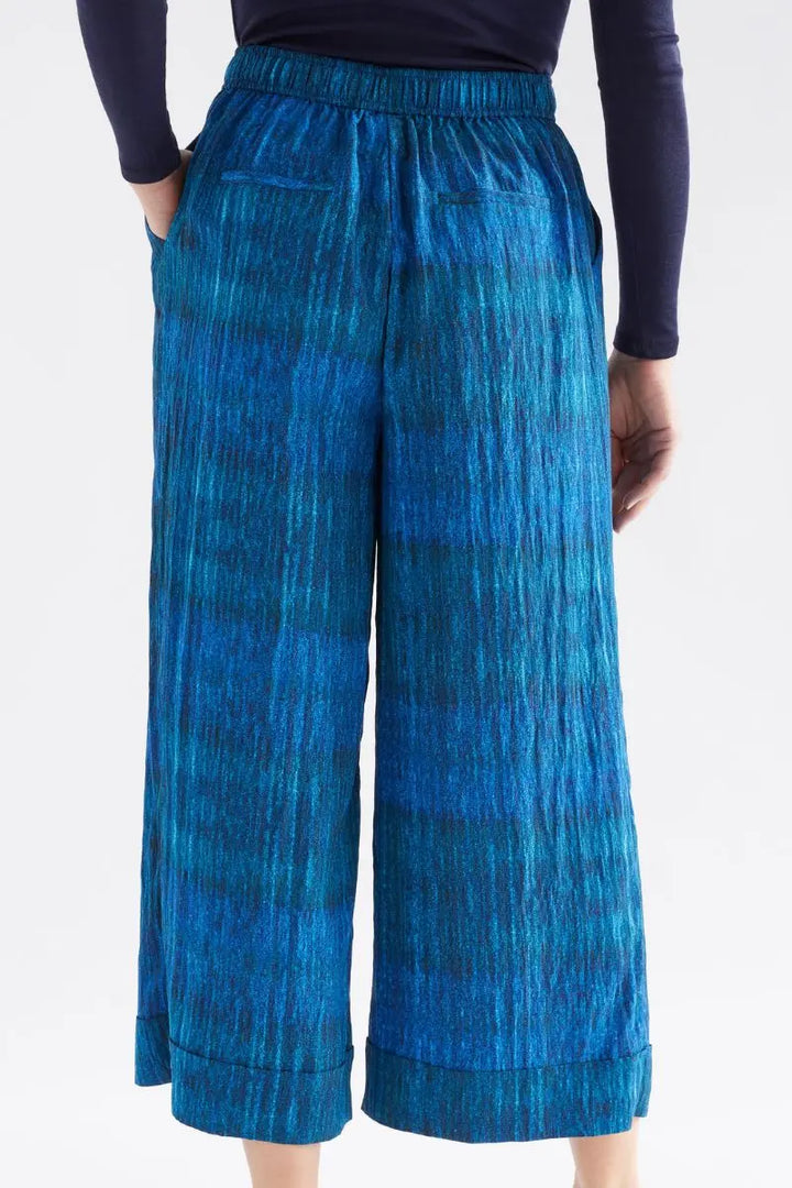 Blue patterned pants worn by a person on a white background