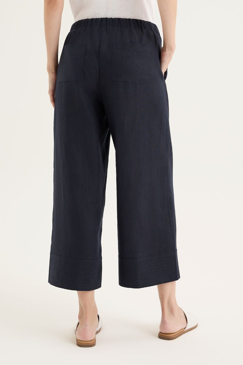 Person wearing navy blue wide-leg pants on a white background