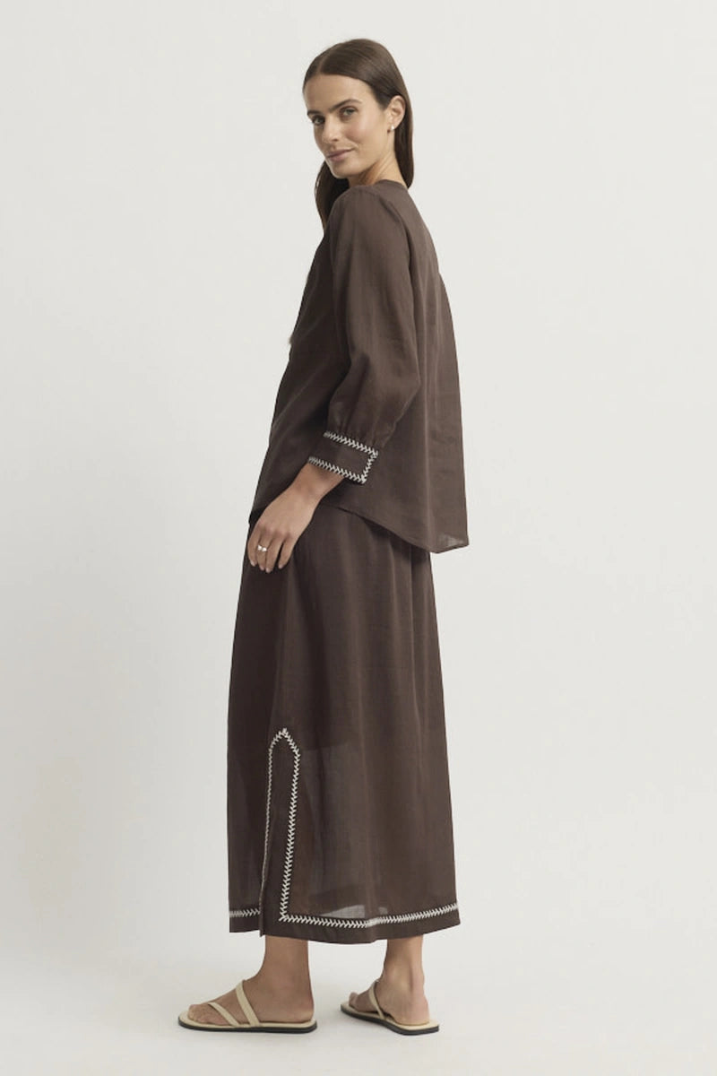 Full-length side model view showing the Grace Blouse worn loose with coordinating Coco trousers and the curved hem visible from the side.