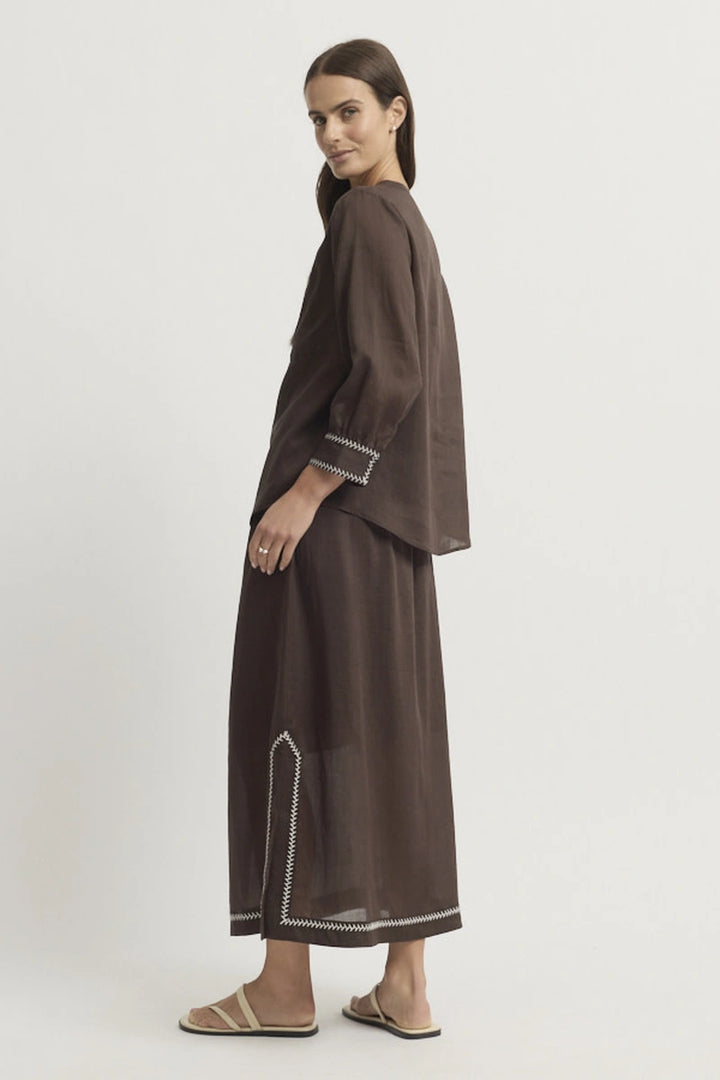 Full-length side model view showing the Grace Blouse worn loose with coordinating Coco trousers and the curved hem visible from the side.
